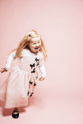 Laughing little girl running in front of pink background - IPF000261