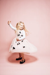 Smiling blond little girl dancing in front of pink background - IPF000262
