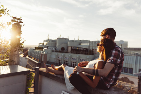 Österreich, Wien, Junges Paar genießt romantischen Sonnenuntergang auf Dachterrasse, lizenzfreies Stockfoto