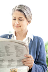 Portrait of smiling matur woman reading a newspaper - RMAF000005