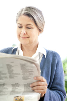 Porträt einer lächelnden, reifen Frau, die eine Zeitung liest - RMAF000005
