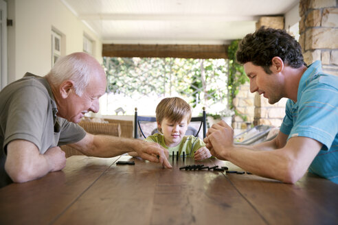 Little boy playing with his father and grandfather domino - RMAF000010