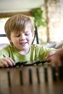 Porträt eines kleinen Jungen, der mit Domino spielt - RMAF000011