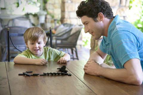 Kleiner Junge spielt mit seinem Vater Domino, lizenzfreies Stockfoto