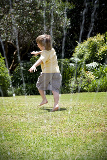 Kleiner Junge spielt mit Rasensprenger im Garten - RMAF000027