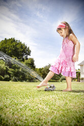 Kleines Mädchen spielt mit Rasensprenger im Garten - RMAF000029