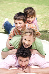 Gruppenbild einer glücklichen Familie, die auf einer Decke im Garten übereinander liegt - RMAF000048
