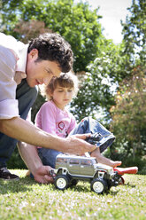 Mann und seine kleine Tochter mit Spielzeugauto im Garten - RMAF000053