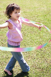 Kleines Mädchen spielt mit Hula-Hoop-Reifen im Garten - RMAF000059