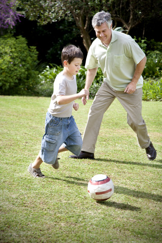 Kleiner Junge spielt Fußball mit seinem Großvater, lizenzfreies Stockfoto