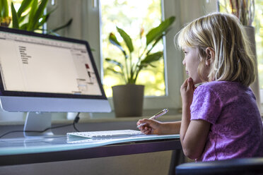 Little girl looking at computer monitor at home - JFEF000733