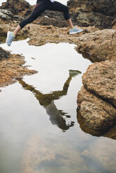 Beine und Wasserspiegelung eines springenden Joggers in der Natur - RAEF000574