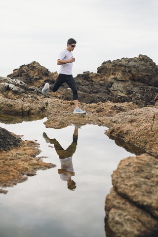 Spanien, Ferrol, Jogger und seine Wasserspiegelung an der Küste, lizenzfreies Stockfoto