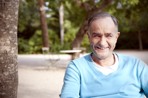Porträt eines lächelnden reifen Mannes, der im Garten sitzt, lizenzfreies Stockfoto
