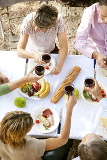 Spanien, Mallorca, fünf Freunde sitzen am gedeckten Tisch im Garten und stoßen mit Rotwein an - RMAF000103