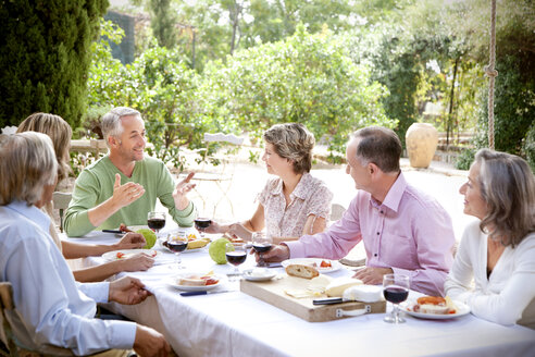 Spanien, Mallorca, sechs Freunde sitzen am gedeckten Tisch im Garten - RMAF000115