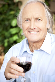 Portrait of relaxed senior man holding glass of red wine - RMAF000118