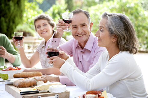 Spain, Mallorca, mature man sitting with friends at laid table in the garden toasting with red wine - RMAF000120