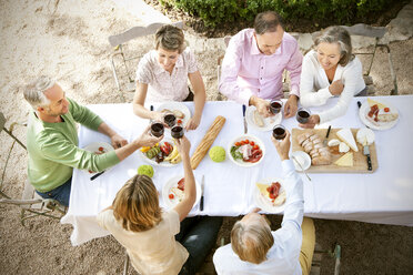 Spanien, Mallorca, sechs Freunde sitzen am gedeckten Tisch im Garten und stoßen mit Rotwein an - RMAF000122