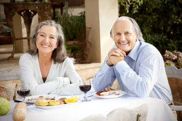 Spain, Mallorca, happy couple sitting at laid table in the garden - RMAF000124
