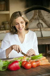 Portrait of smiling woman chopping vegetables - RMAF000142