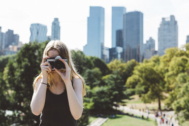 USA, New York City, young woman photographing in Central Park - GIOF000344