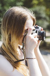 Blonde junge Frau beim Fotografieren im Freien - GIOF000345