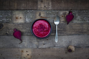 Bowl of beetroot soup garnished with beetroot sprouts on dark wood - LVF004066