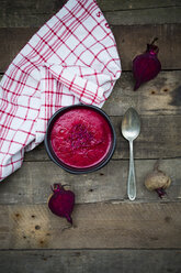 Bowl of beetroot soup garnished with beetroot sprouts on dark wood - LVF004068