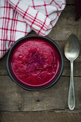 Bowl of beetroot soup garnished with beetroot sprouts on dark wood - LVF004070