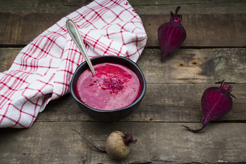 Schale Rote-Bete-Suppe garniert mit Rote-Bete-Sprossen auf dunklem Holz, lizenzfreies Stockfoto