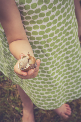 Kleines Mädchen hält Weinbergschnecke in der Hand, lizenzfreies Stockfoto