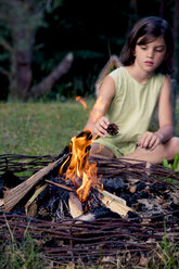 Girl sitting on a meadow behind a camp fire - LVF004080