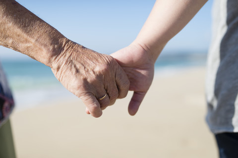 Elderly woman and young woman holding hands on the beach stock photo