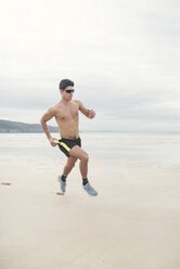 Spain, Ferrol, young man running fast on the beach - RAEF000599