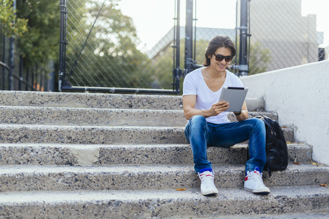 Man sitting on steps using digital tablet stock photo