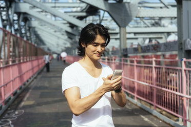 USA, New York City, Mann auf der Williamsburg Bridge in Brooklyn beim Überprüfen des Handys - GIOF000375