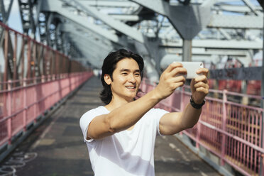 USA, New York City, Mann auf der Williamsburg Bridge in Brooklyn, der ein Selfie macht - GIOF000376