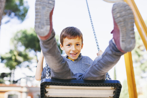 Glücklicher Junge auf einer Schaukel auf dem Spielplatz - EBSF000995