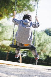 Rückansicht eines Jungen auf einer Schaukel auf dem Spielplatz - EBSF000997