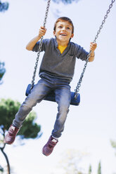 Glücklicher Junge auf einer Schaukel auf dem Spielplatz - EBSF000999