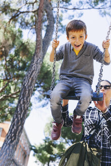 Mutter schiebt ihren Sohn auf einer Schaukel auf dem Spielplatz - EBSF001001