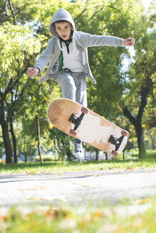 Junge macht einen Skateboardtrick im Park im Herbst - DEGF000563