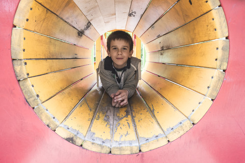 Junge in einem Tunnel auf dem Spielplatz, lizenzfreies Stockfoto