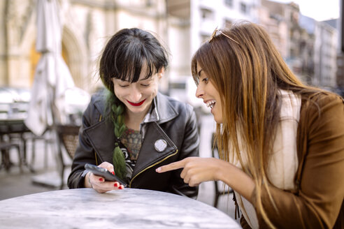 Spanien, Gijon, Zwei Freunde im Café schauen auf ihr Smartphone - MGOF000966