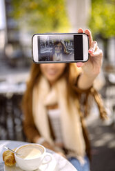 Spanien, Gijon, Junge Frau in Café macht Selfie mit Smartphone, Nahaufnahme - MGOF000972