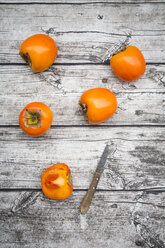 Whole and sliced kaki persimmons and a kitchen knife on wood - LVF004096