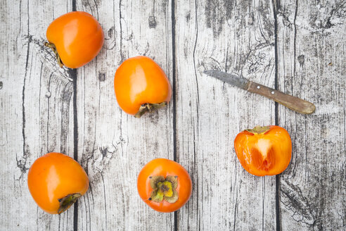 Whole and sliced kaki persimmons and a kitchen knife on wood - LVF004097