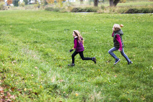 Junge und Mädchen laufen über eine Wiese - SARF002268