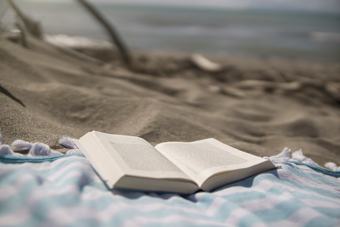 Italien, Toskana, Maremma, Buch auf Strandtuch, lizenzfreies Stockfoto